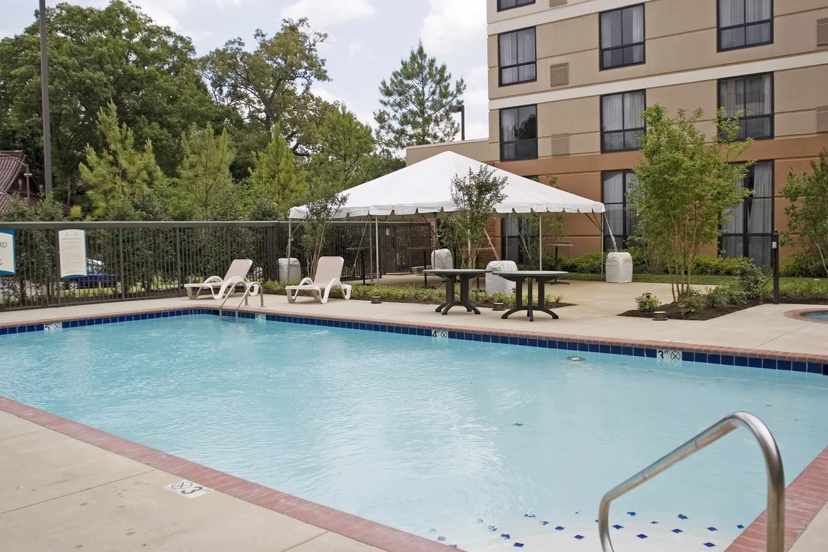 An inviting outdoor pool area complete with lounge chairs, a tent for shade, and lush surrounding greenery. The space is perfect for hosting social gatherings, relaxing, or enjoying a family barbecue by the pool.